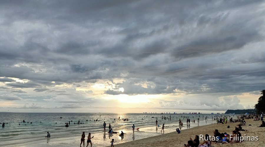 White Beach de Boracay a última hora, con gente en la arena y el sol bajo las nubes